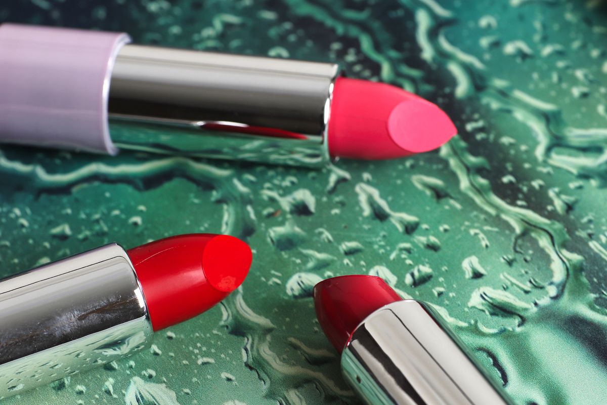 Matte liquid lipstick, satin bullet, and gloss wand arranged on linen