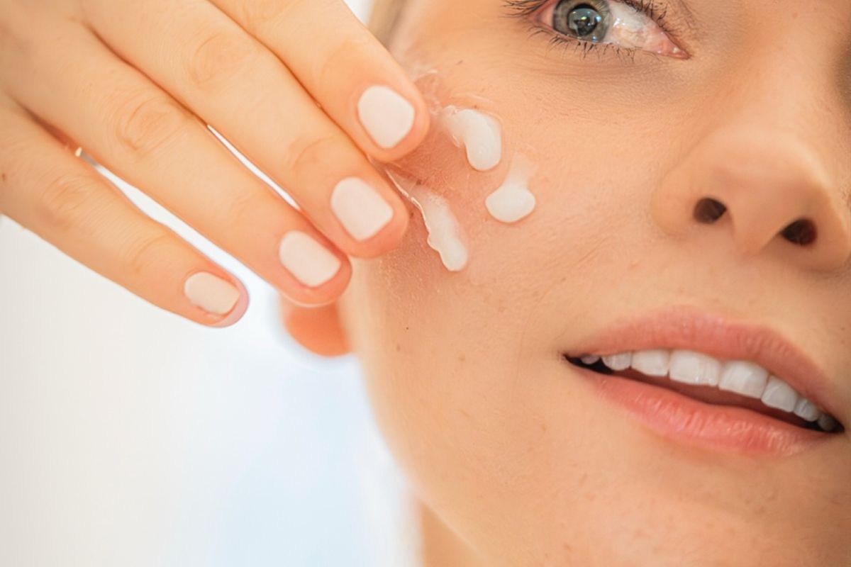 Cleansing balm, micellar water bottle, oil, and cloth on a bathroom counter